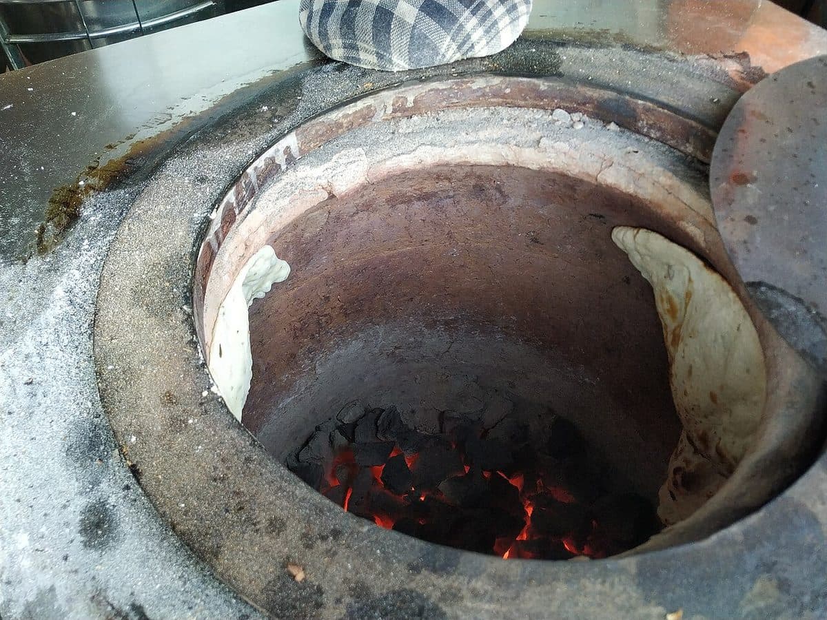 Naanbrød i en tandoorovn over kullglød