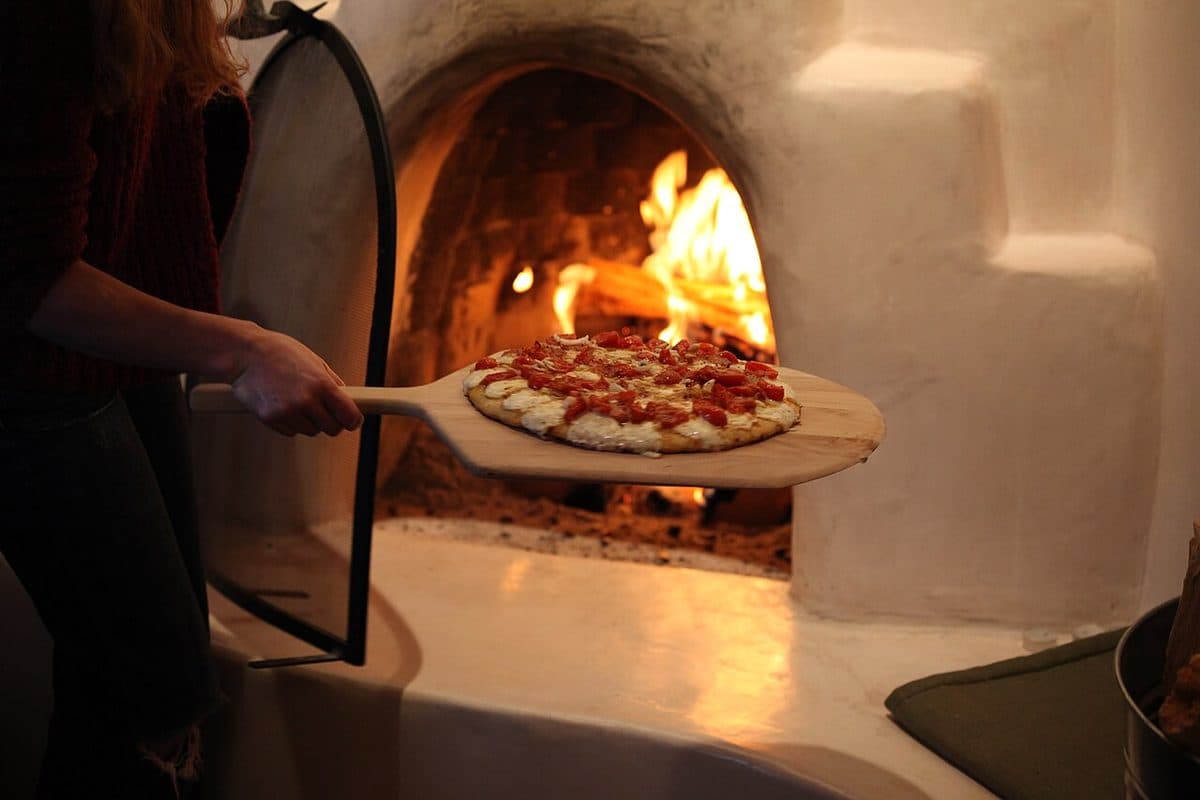 En pizzaiolo setter en pizza inn i ovnen