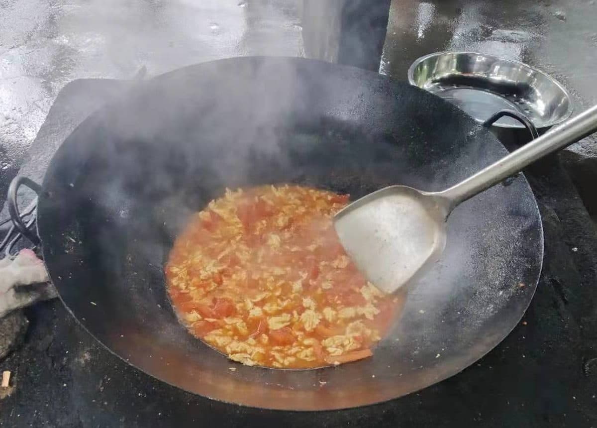 En wok med mat som putrer over en gassbrenner